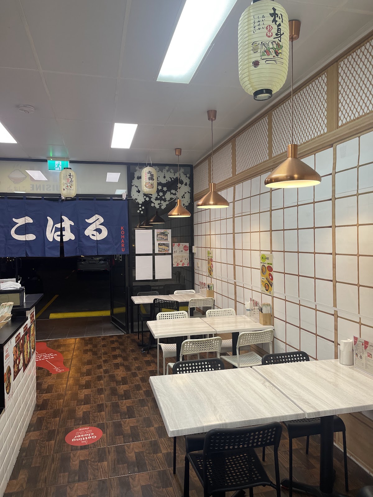 Inside KOHARU: the navy こはる curtain at the door, shoji-style wall tiles, copper lamps and paper lanterns